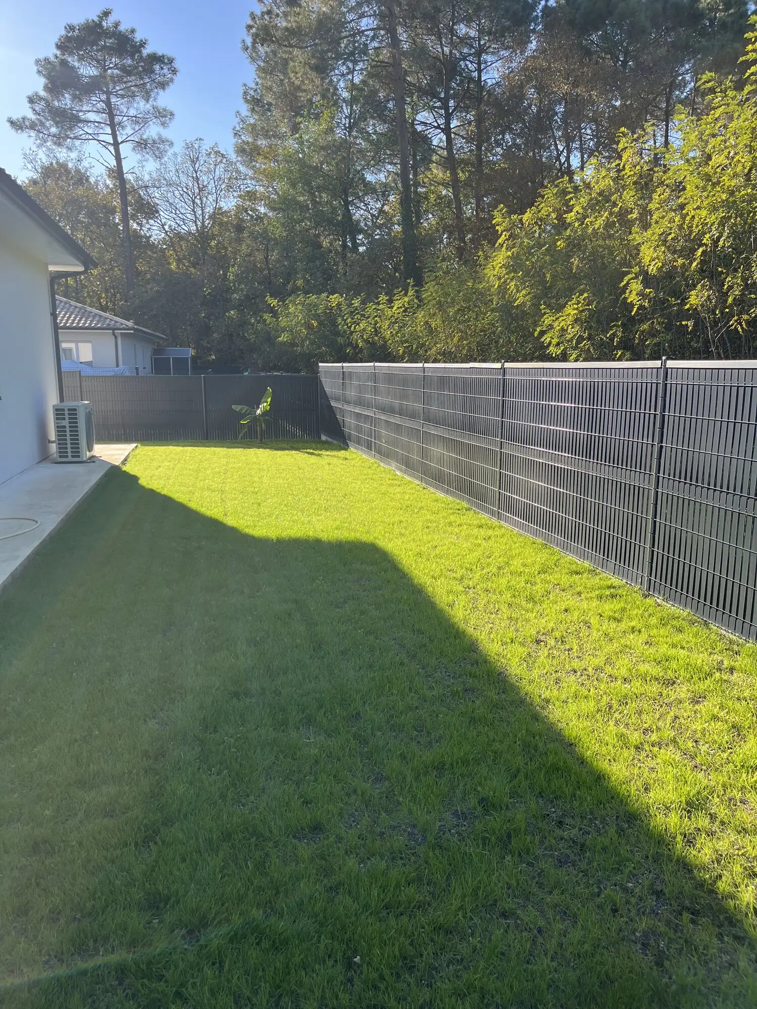 Le même angle du jardin couvert de gazon levé, le long de la clôture