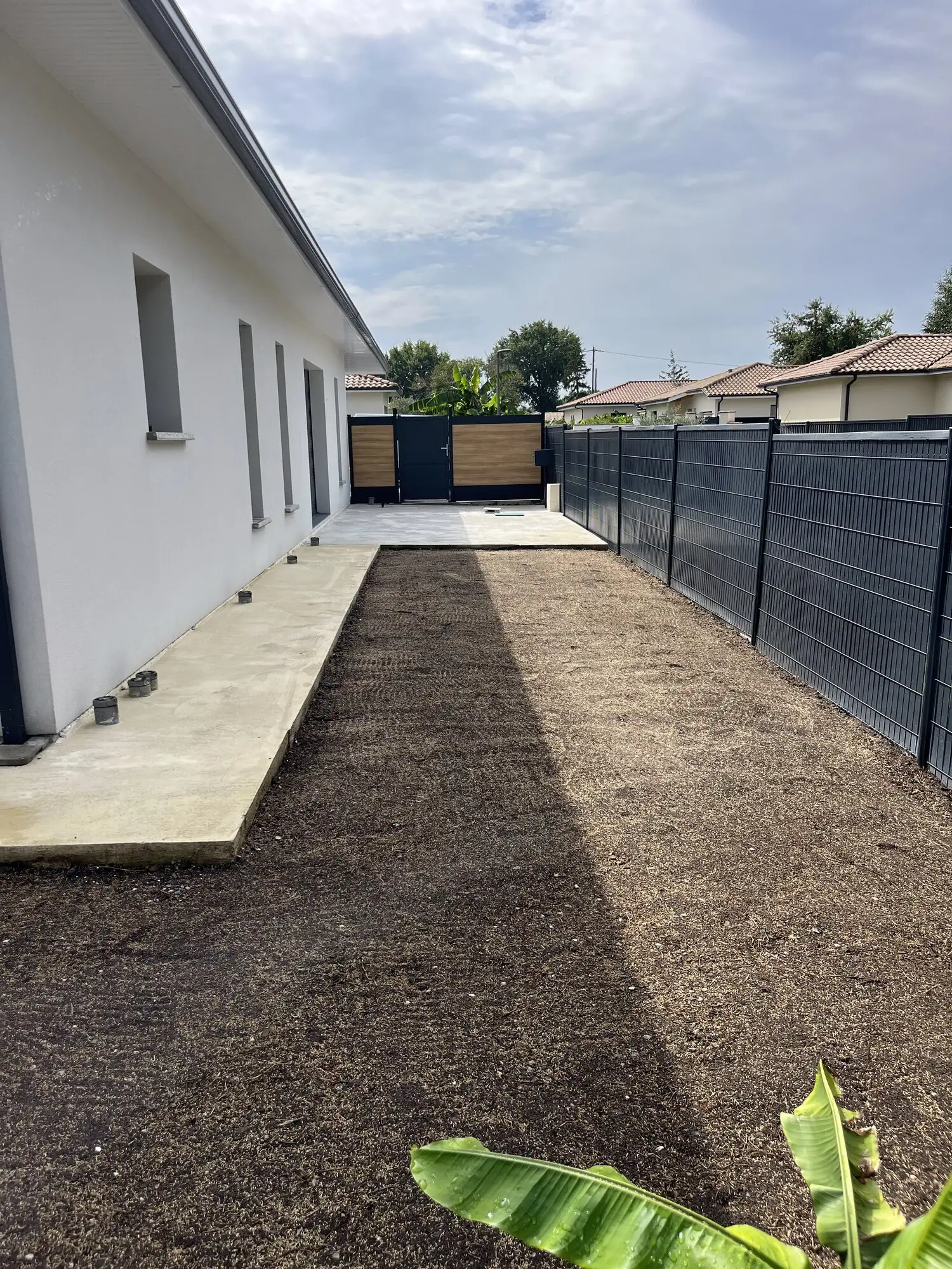 Bande de terre nue préparée et nivelée le long d'une maison neuve, avant semis