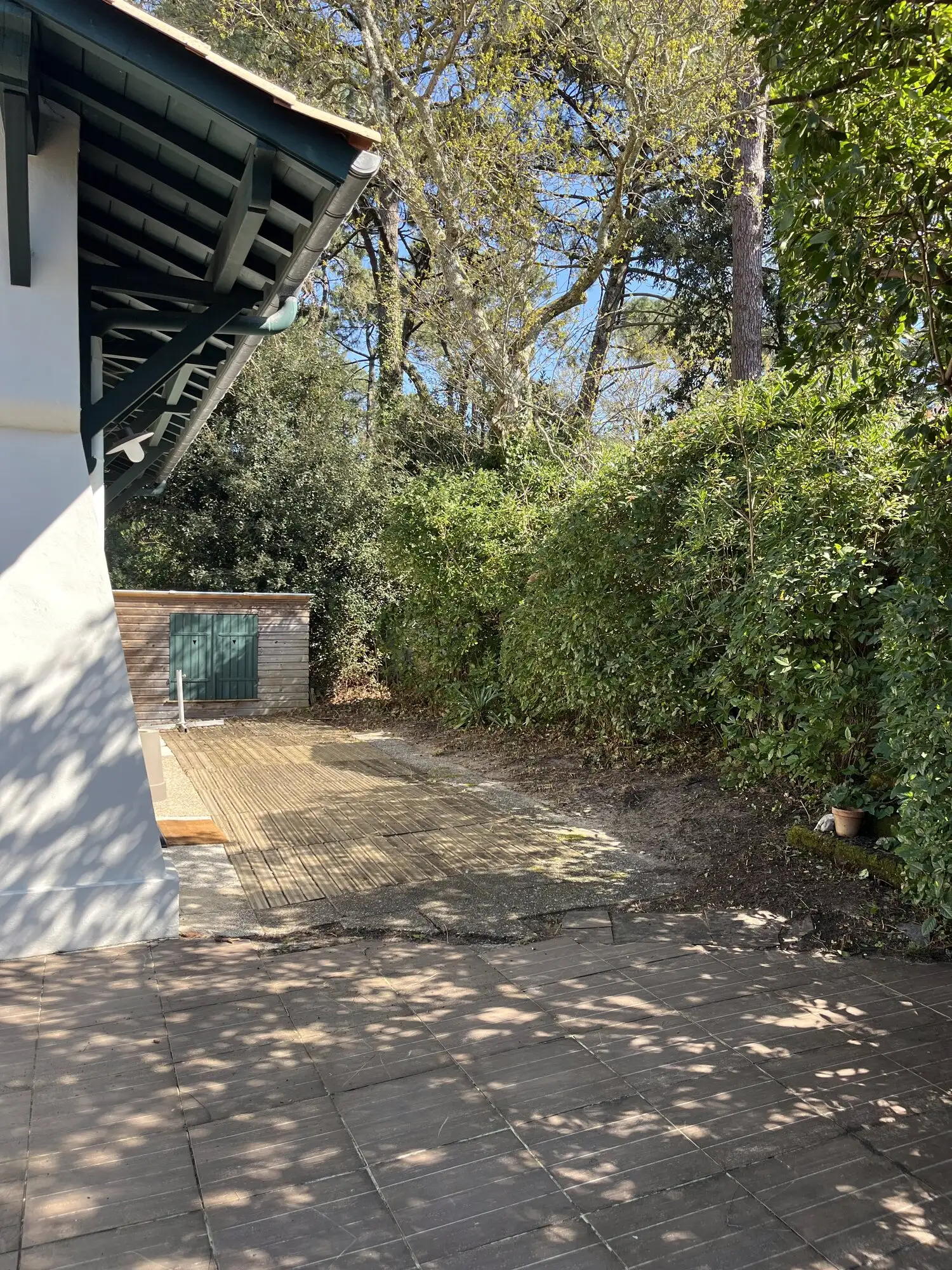 Terrasse dallée à l'arrière de la villa, dégagée des aiguilles de pin